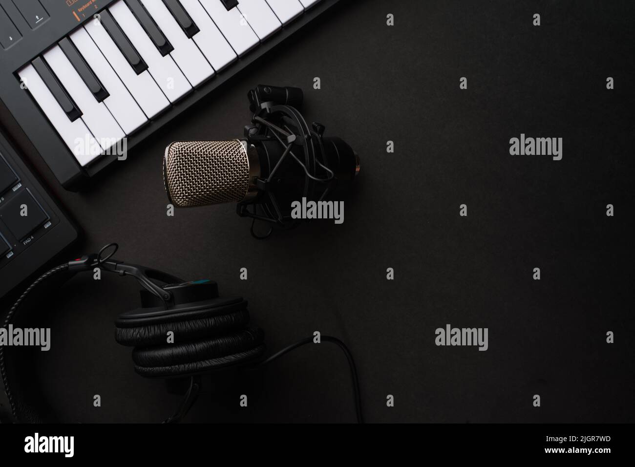Modern synthesizer midi keyboard and studio microphone on a gray