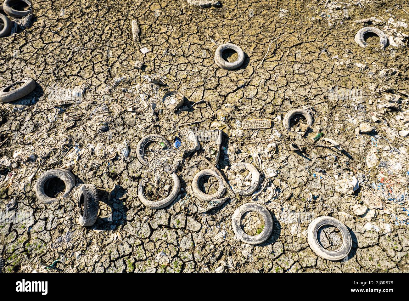 Old tire illegally abandoned in Po river visible due to drought. Carmagnola, Italy - July 2022 Stock Photo