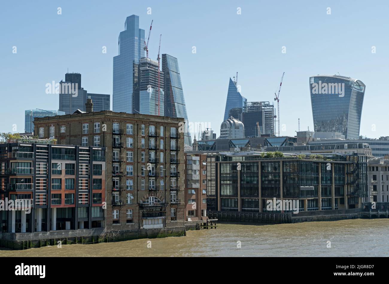 View of construction of the City of London skyline behind the old industrial buildings on the Thames. London - 10th July 2022 Stock Photo