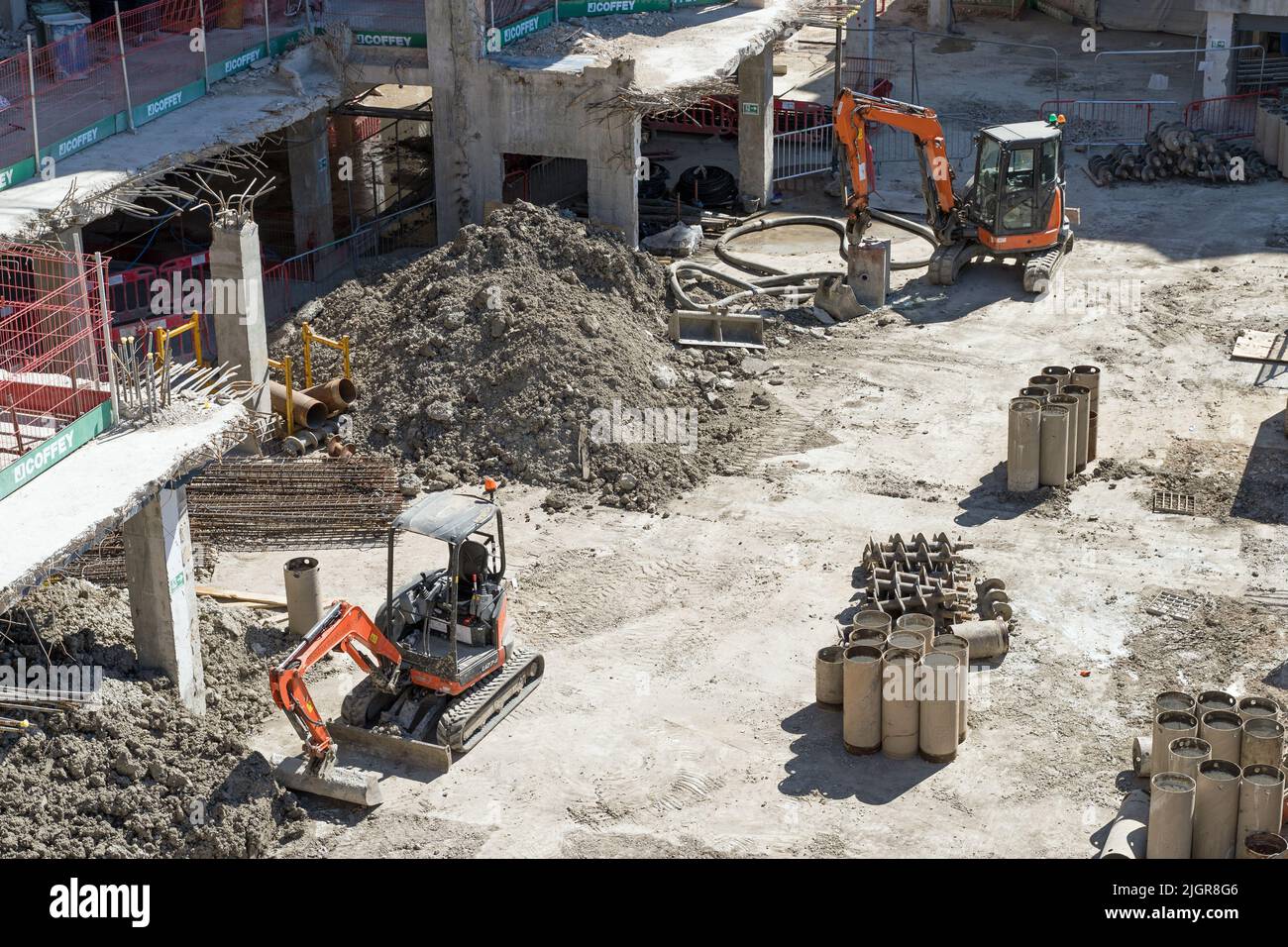 Two mechanical excavators on a construction site surrounded by rubble and piling columns. London - 10th July 2022 Stock Photo