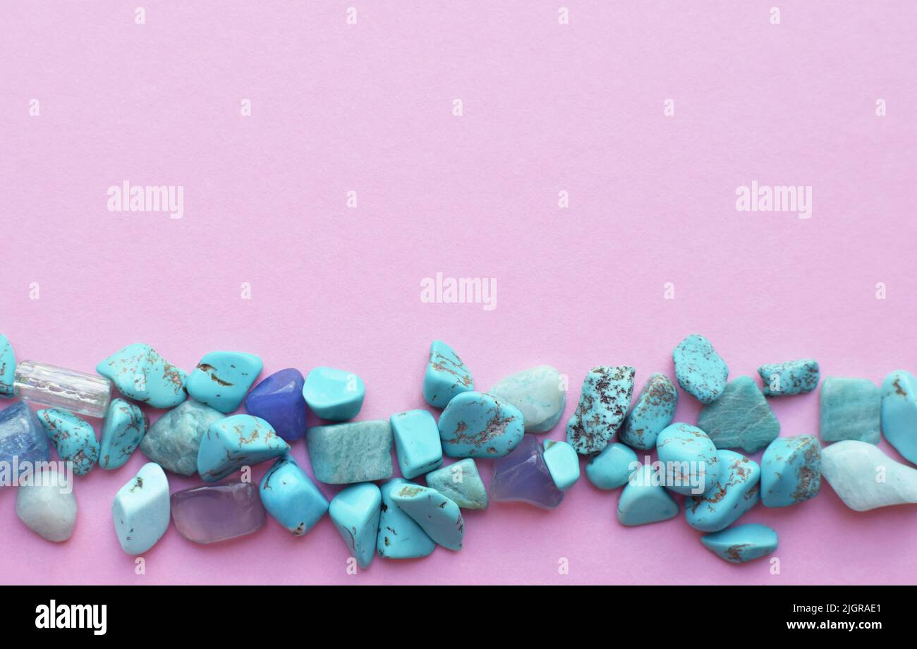 Turquoise semi-precious stones are piled on a pink background. Place for text Stock Photo