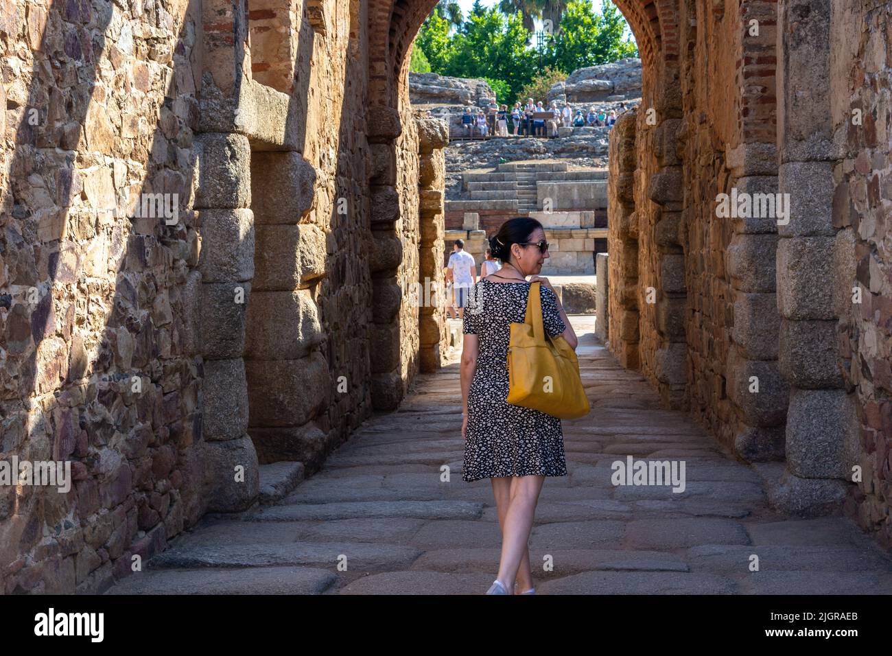 Woman advancing through a stone corridor towards the Roman Amphitheater in Mérida, as if she were an actress or dancer who goes on stage Stock Photo