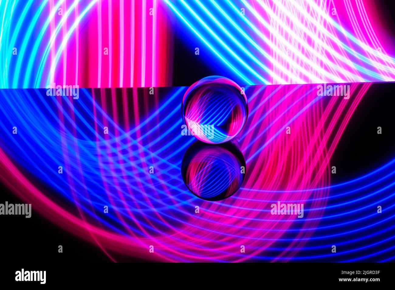 A crystal ball on a reflective surface with colorful neon lighting