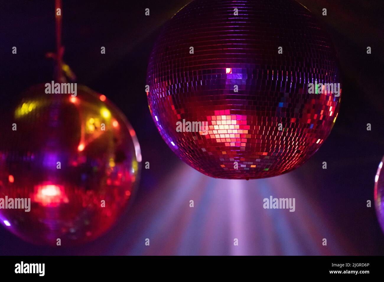 A closeup shot of disco balls hanging from the ceiling under bright