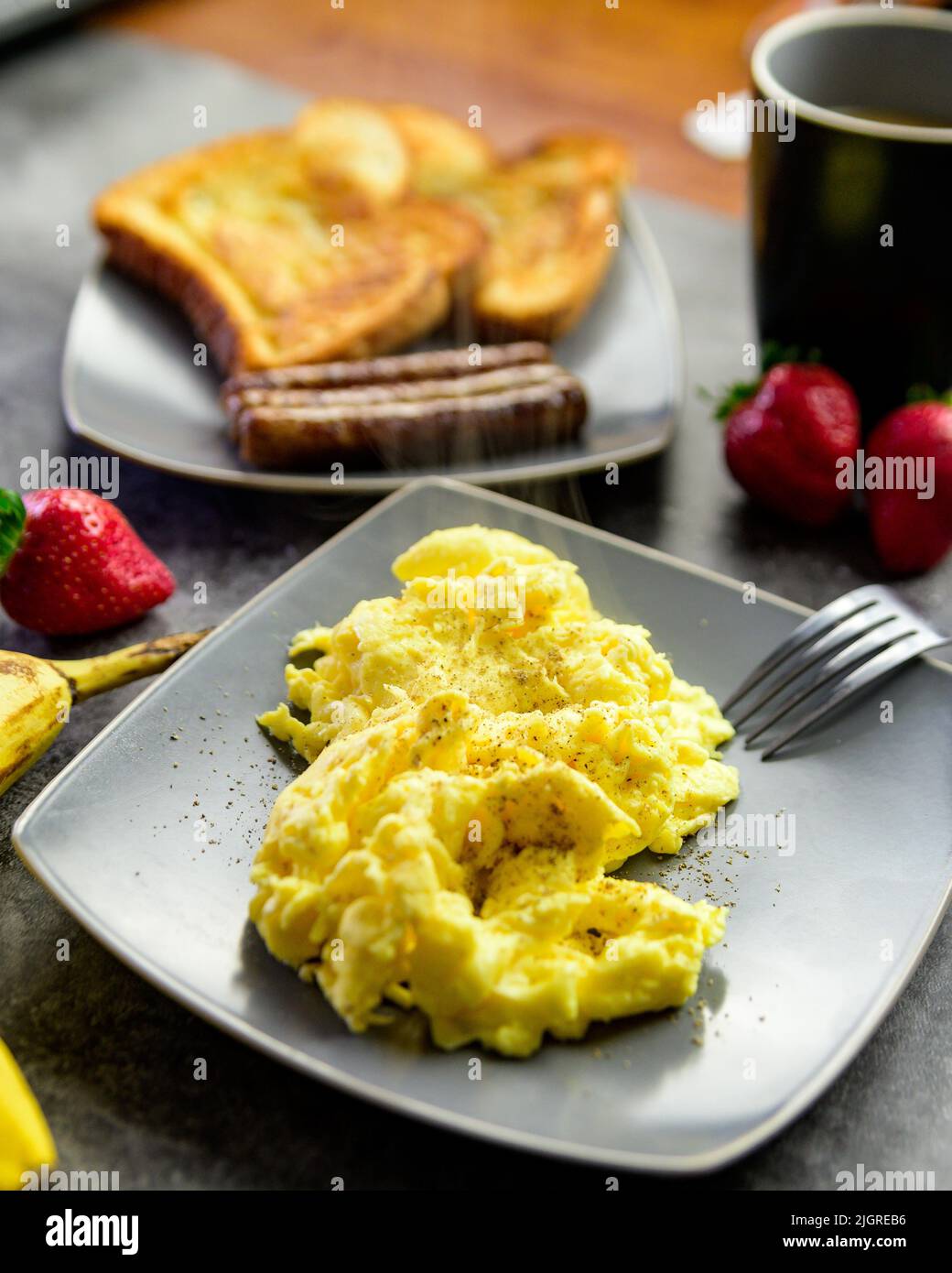 A vertical close-up shot of scrambled eggs on a plate next to French ...