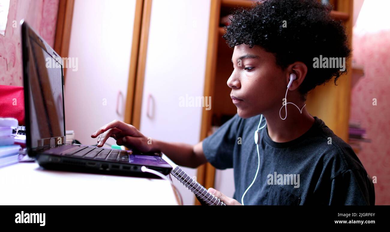 Child doing homework at home in front of laptop. Black ethnicity kid ...