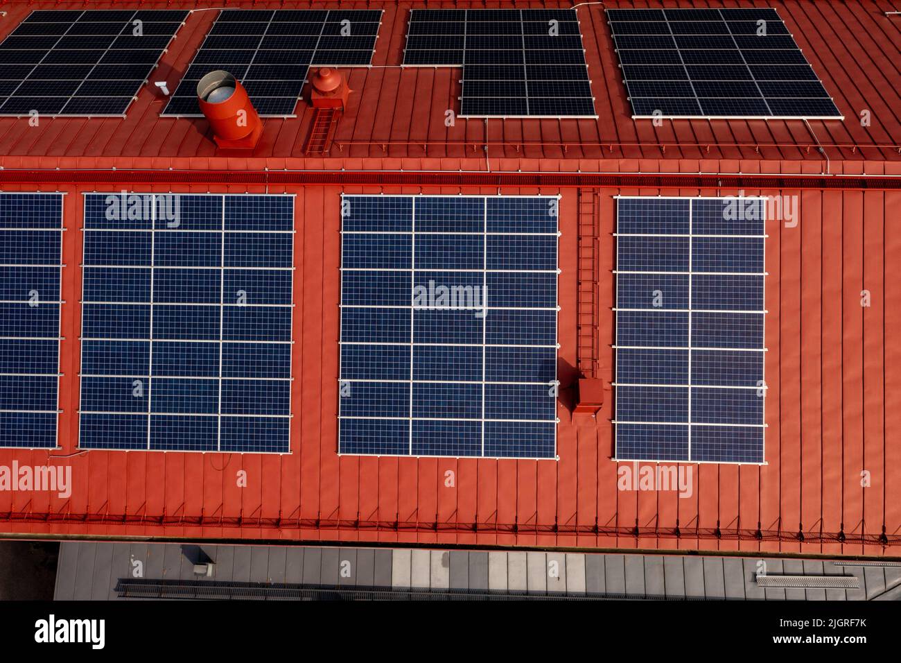 Aerial view above solar panels on a red building rooftop - birdseye, drone shot Stock Photo