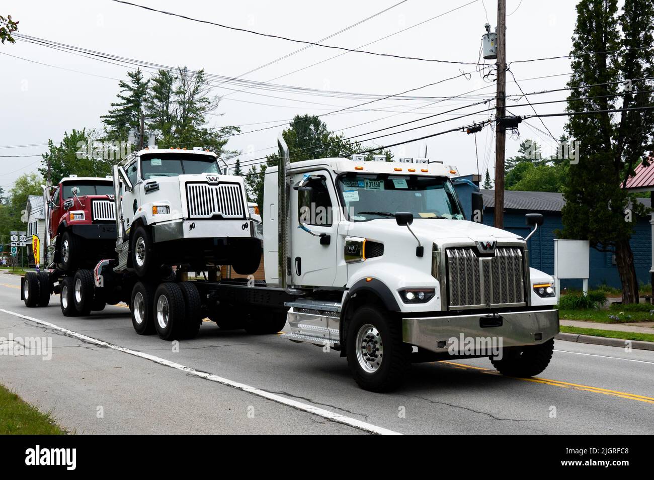 A Western Star semi truck hauling two semi trucks in piggyback fashion through Speculator, NY USA Stock Photo