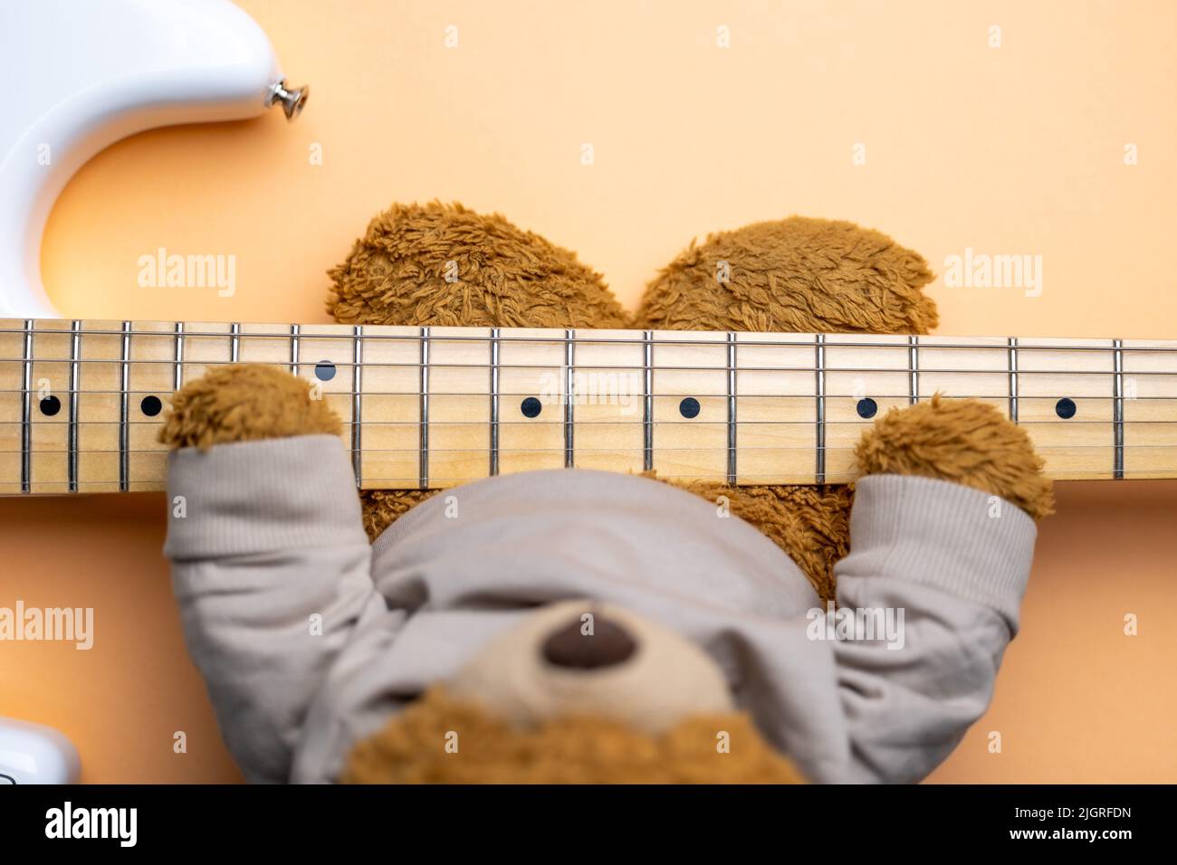Teddy bear playing guitar. Top down view. Plush toy with the Guitar neck in Focus. Stock Photo