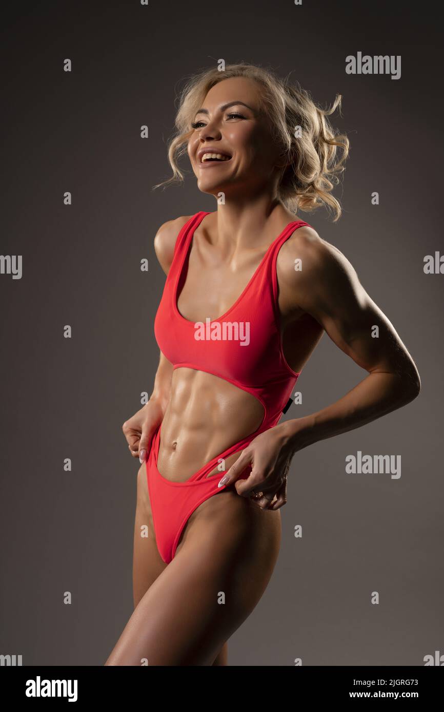 Cheerful muscular woman in swimwear standing in studio Stock Photo