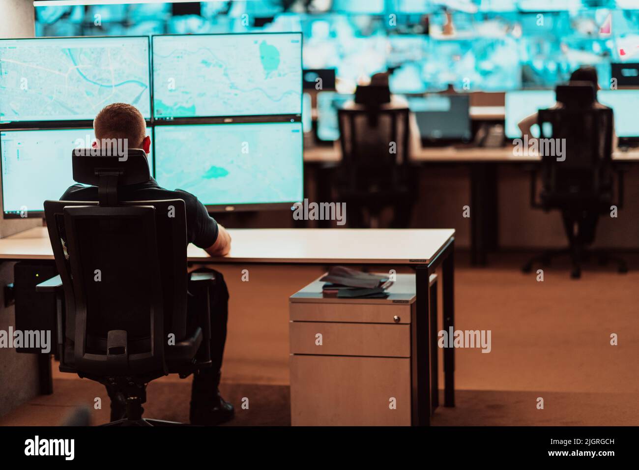 Male security operator working in a data system control room offices