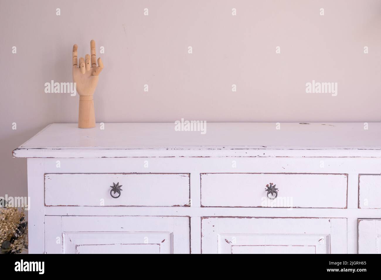 Vintage room design. Antique white cupboard, wooden mannequin hand and empty beige wall with copy space Stock Photo