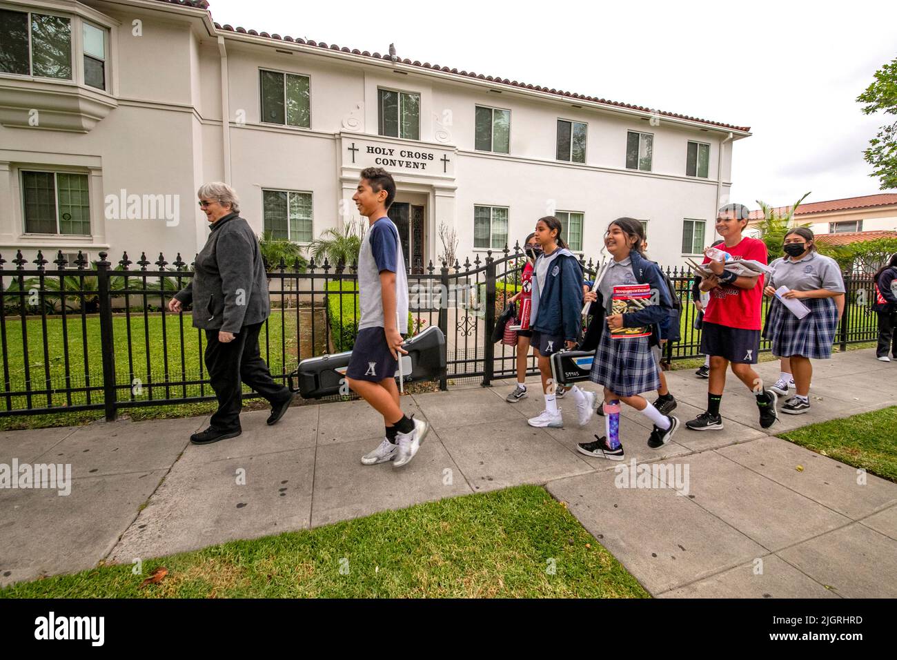 Members of the student orchestra of a Santa Ana, CA, parochial school follow the school principal back to class after rehearsal. Note convent in backg Stock Photo