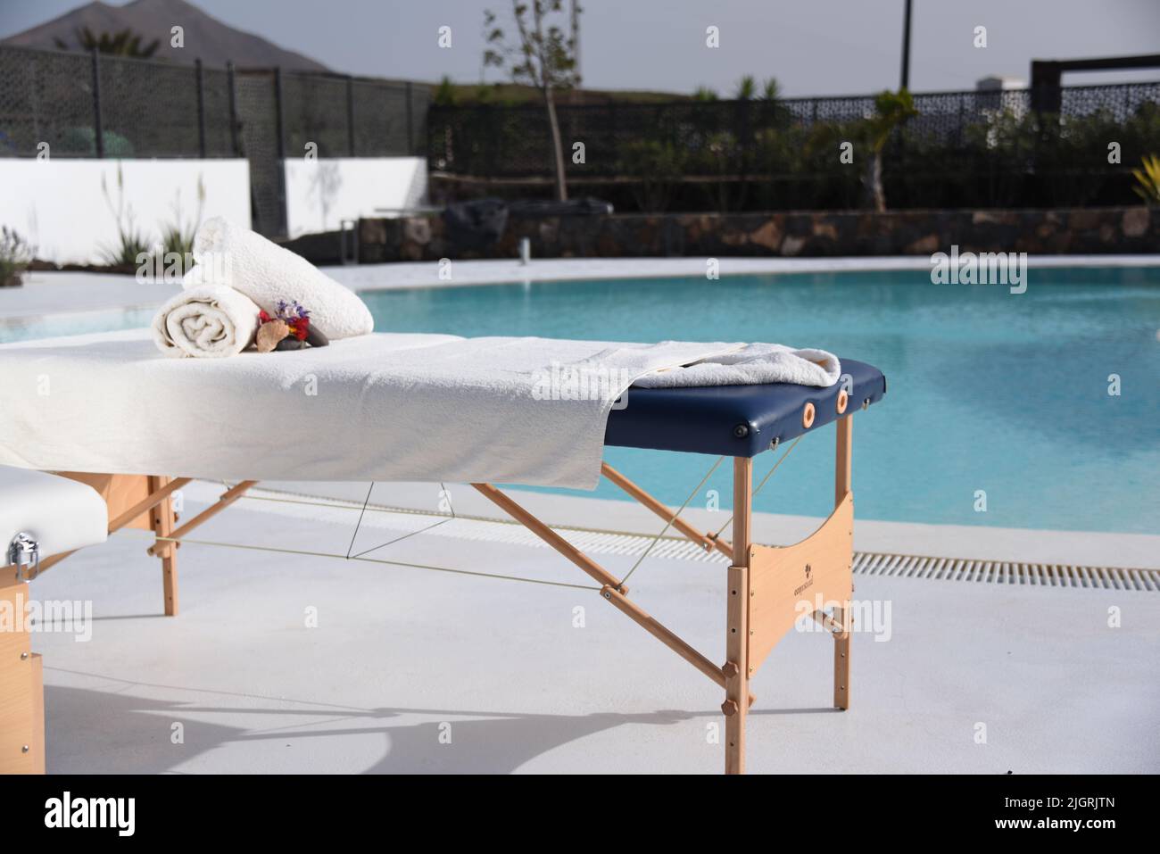 A scenic view of a massage table with towels poolside in sunny weather Stock Photo