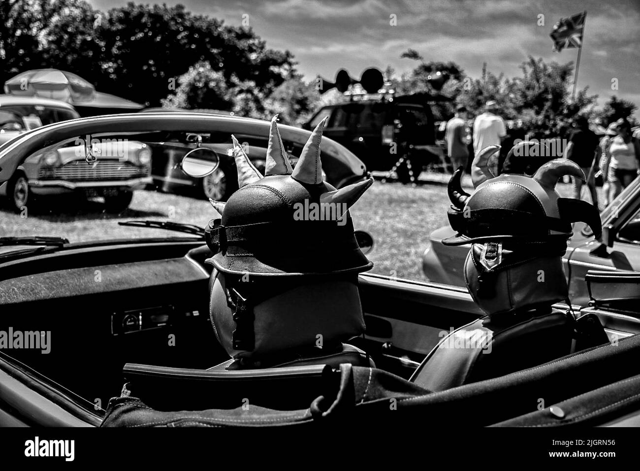 A grayscale of a  classic vintage car with two mohawk helmets attached to its seats Stock Photo