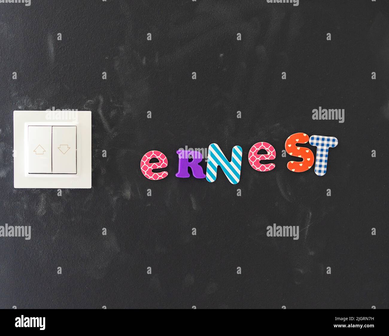 A closeup shot of Ernest's name on a black wall made with stickers