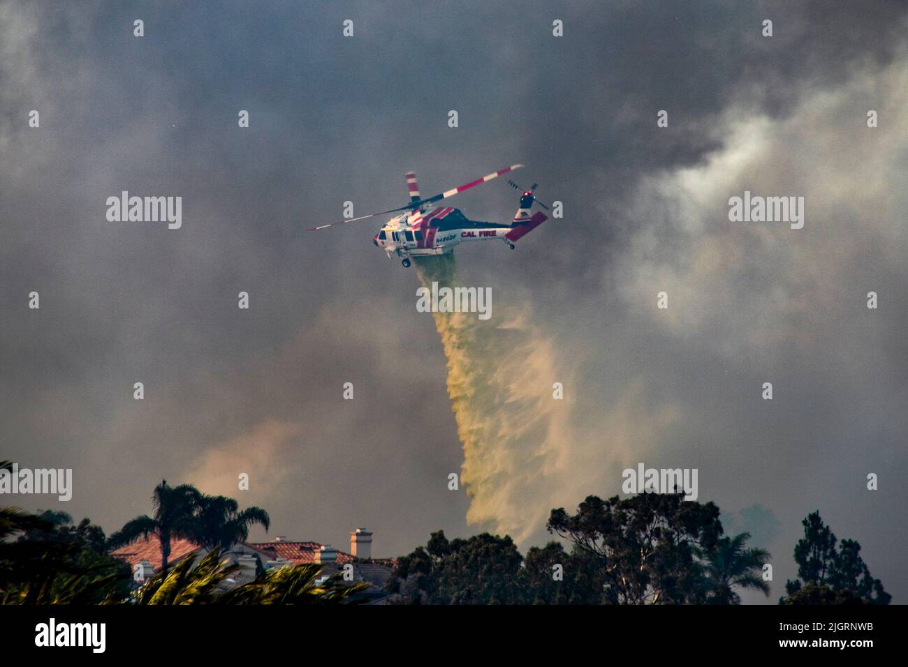 A fire department helicopter drops fire retardant on a burning suburban home in Laguna Niguel, CA. Stock Photo