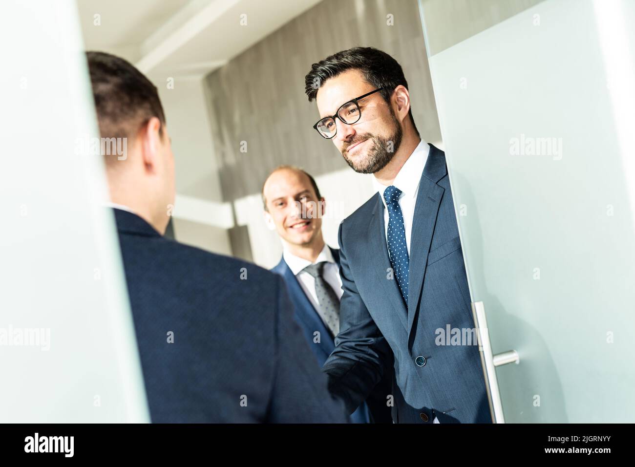 Group of confident business people greeting with a handshake at business meeting in modern office or closing the deal agreement by shaking hands. Stock Photo