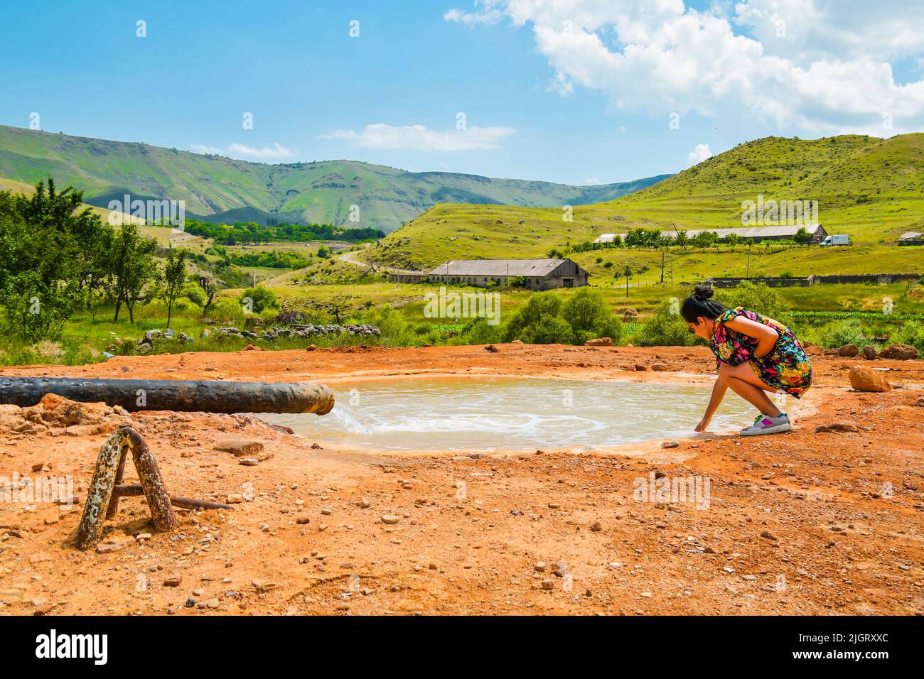 Tourist stand and touch Hot mineral springs from underground pipe on