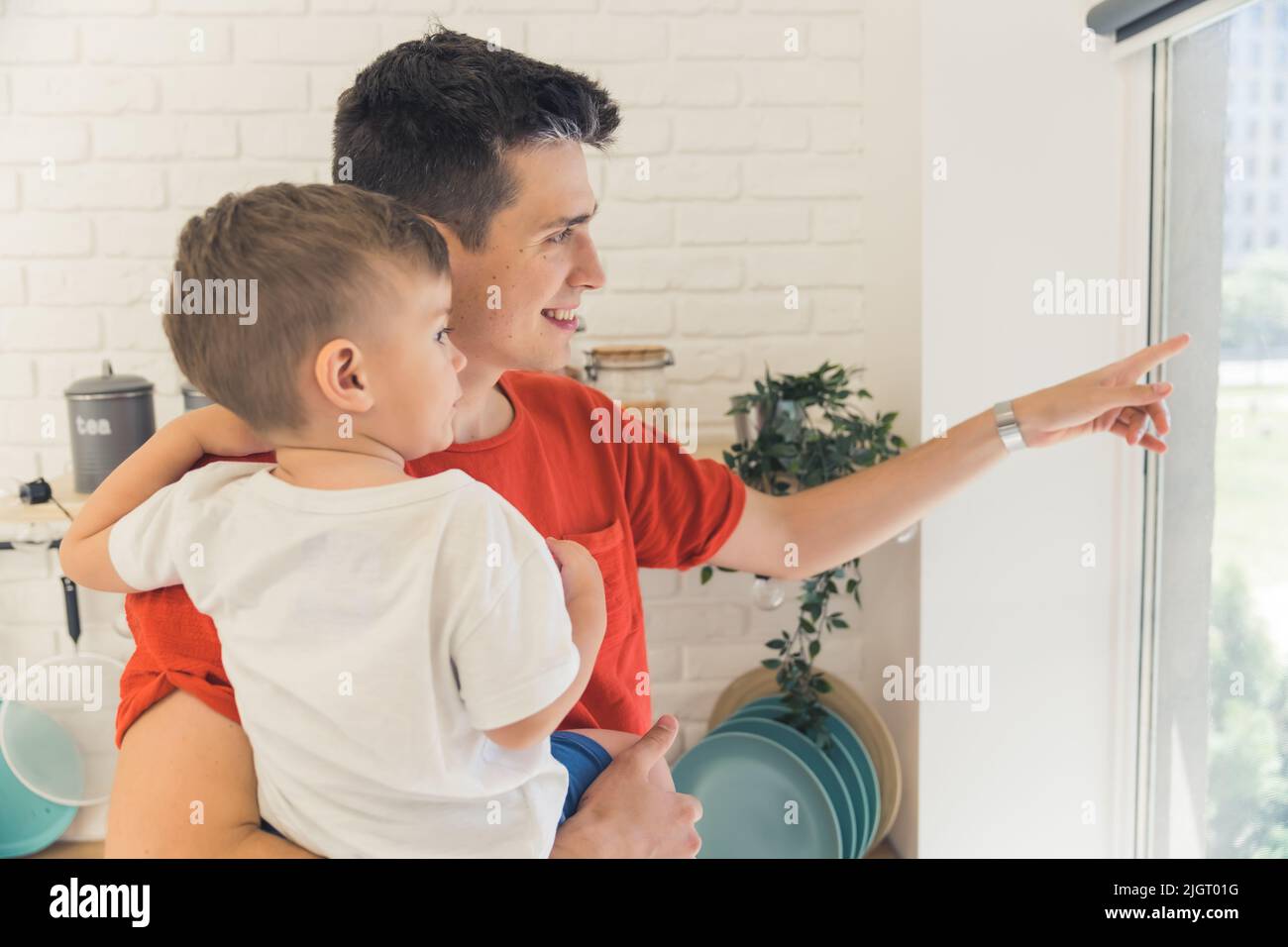 just look over there - young father looking out of the window with his little son, medium closeup. High quality photo Stock Photo