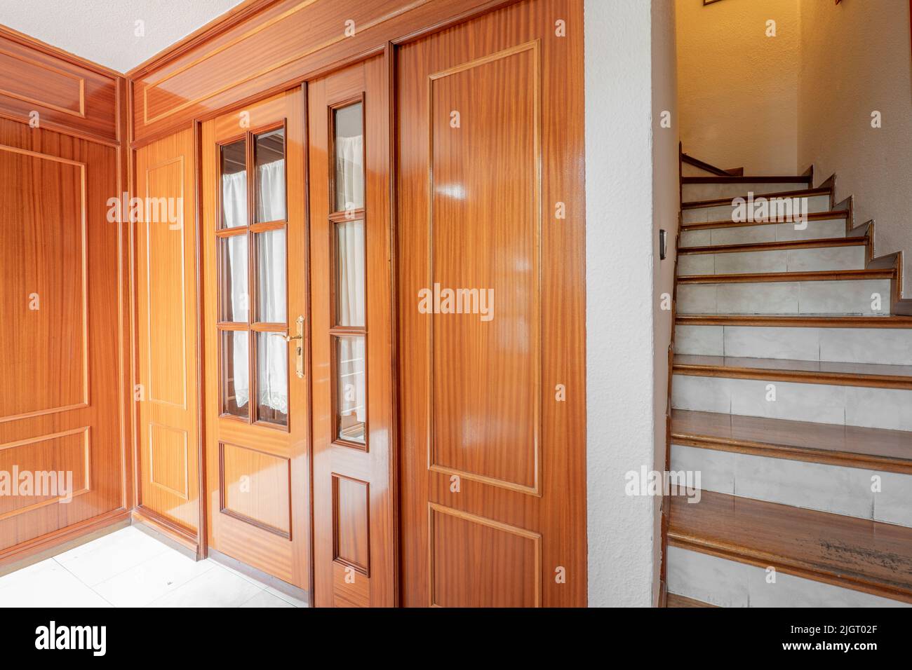 Hallway of a house with wooden doors and stairs with matching wooden