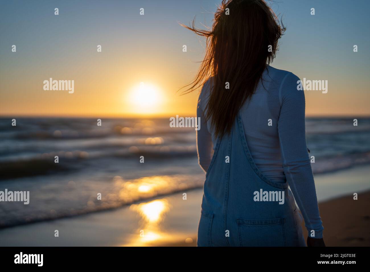 woman watches the sunset while walking on the beach Stock Photo - Alamy