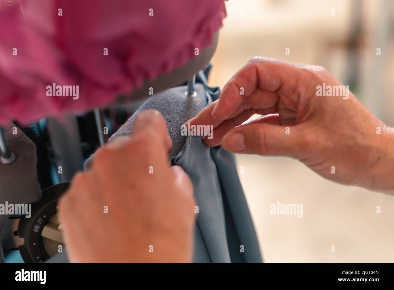 detail of the hands of a seamstress attaching a garment to a mannequin with a pin Stock Photo
