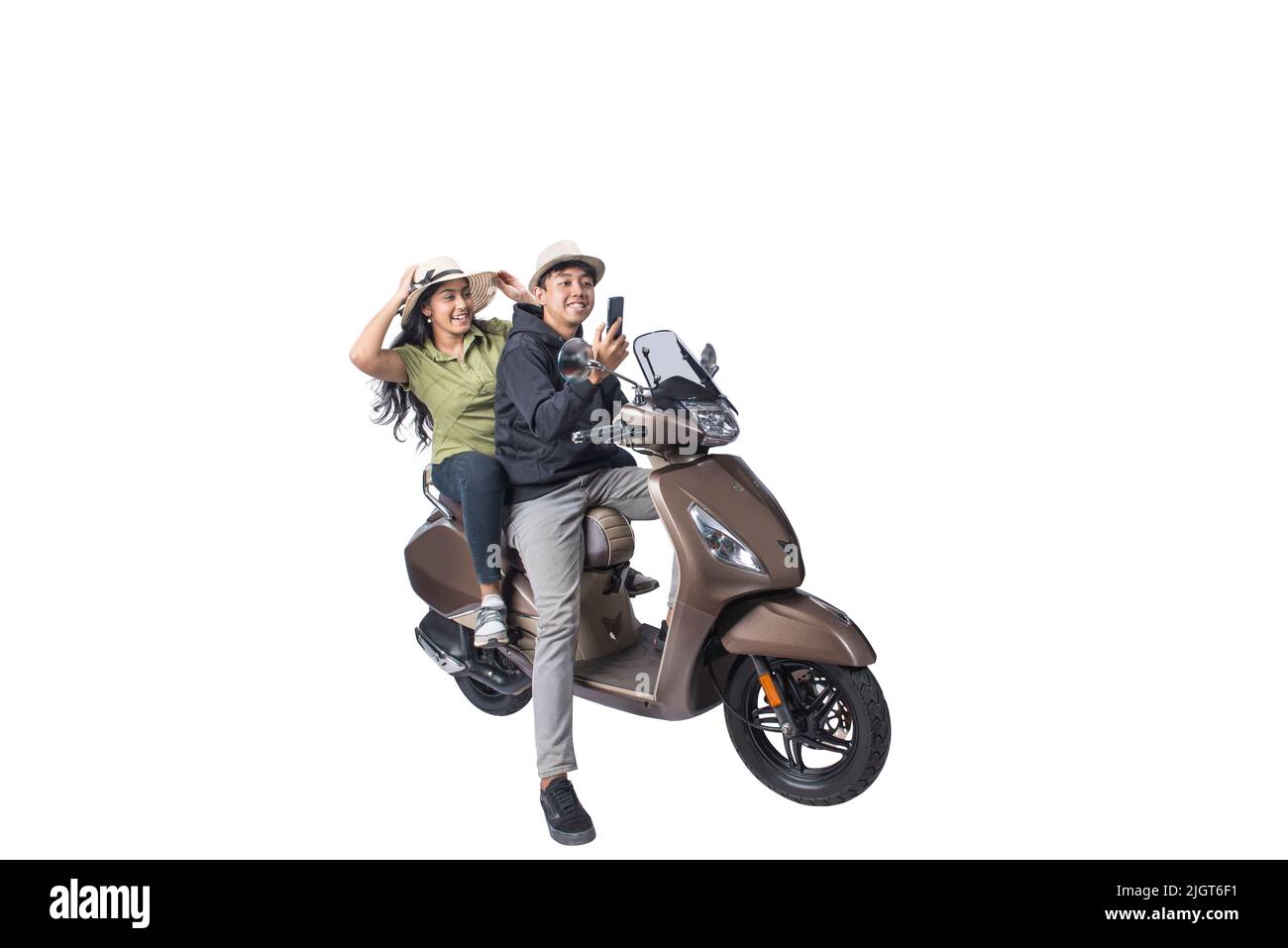 An Asian couple with a hat is sitting on a scooter and holding a mobile phone isolated over white background Stock Photo