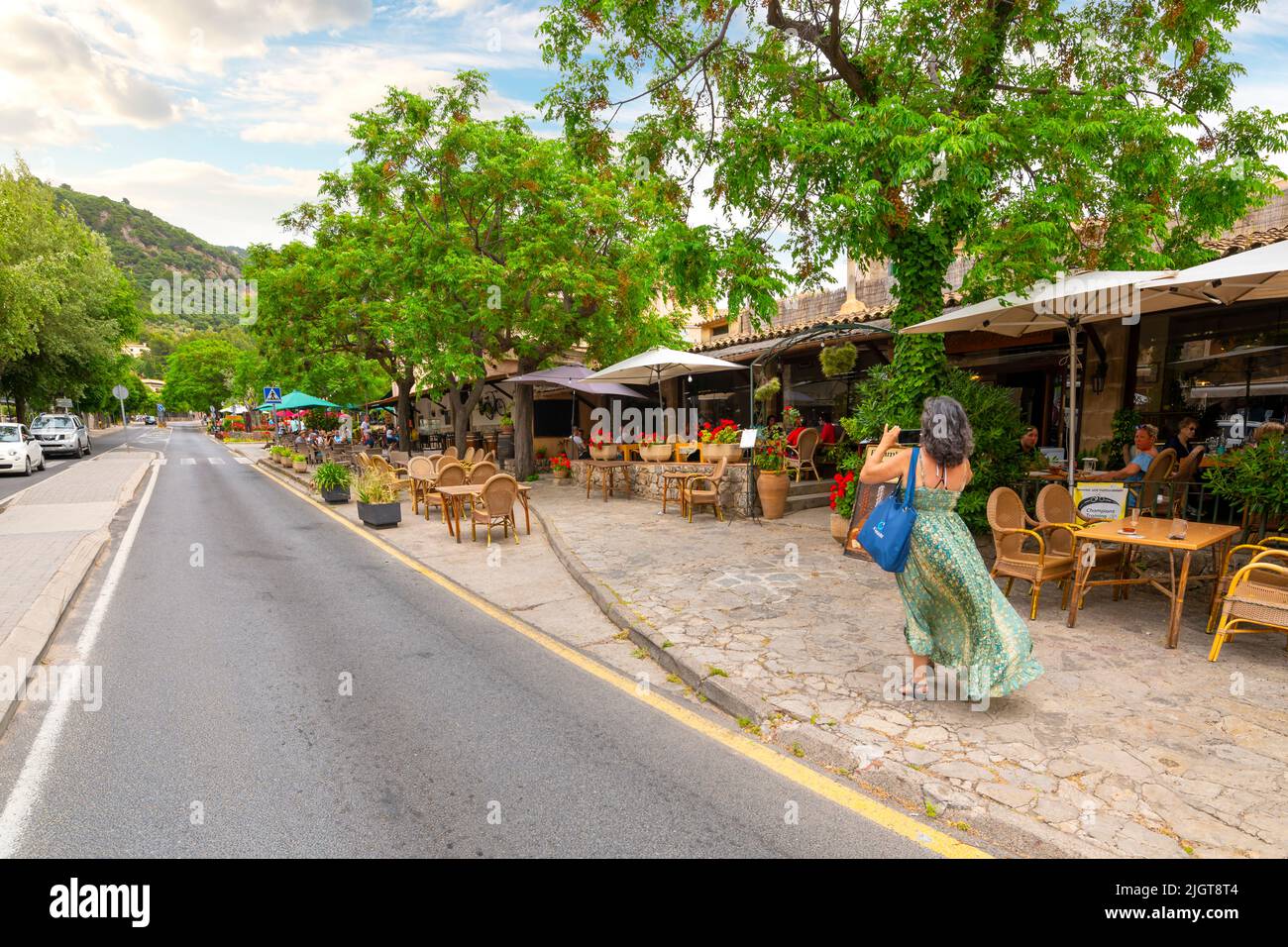 One of the many picturesque tree lined streets of shops and cafes in the hilltop village of Valldemossa, Spain, on the island of Mallorca, Spain. Stock Photo