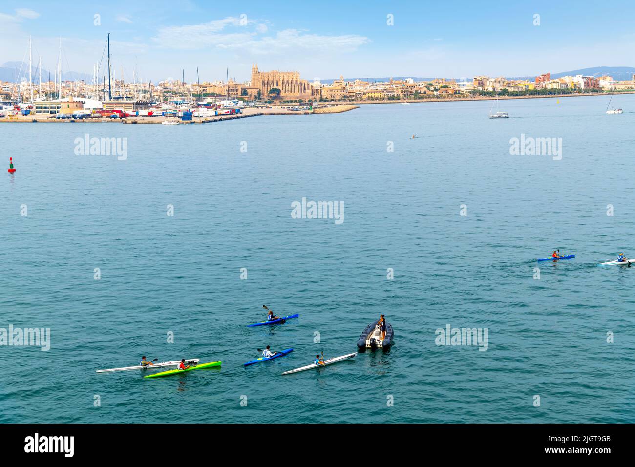 A group of kayers and a small boat in the Mediterranean Sea with the city of Palma de Mallorca, Spain in view on the island of Mallorca. Stock Photo