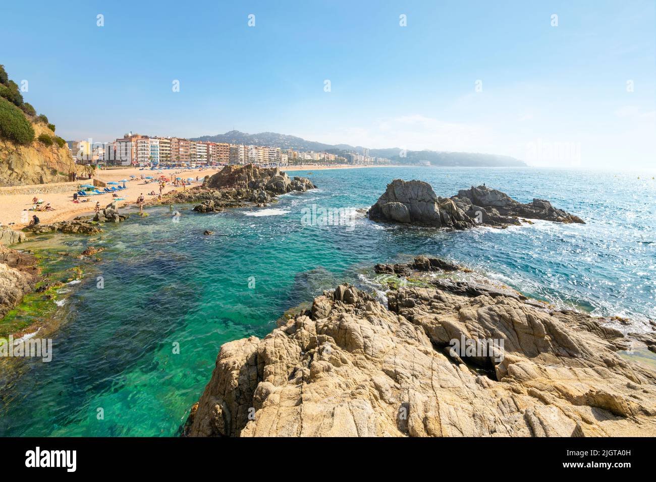 View of the sandy beach, rocky shoreline and resort town of Lloret de Mar, Spain, on the Costa Brava coast of the Mediterranean Sea. Stock Photo