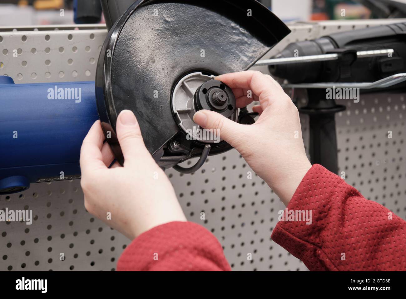 Woman in a building materials store chooses to buy an electric circular saw Stock Photo