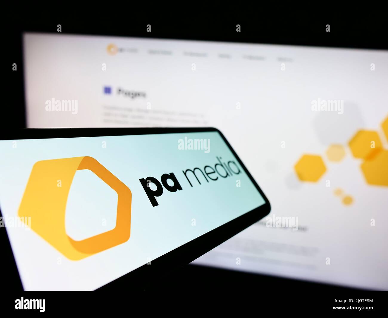 Mobile phone with logo of British news agency PA Media Group on screen in front of business