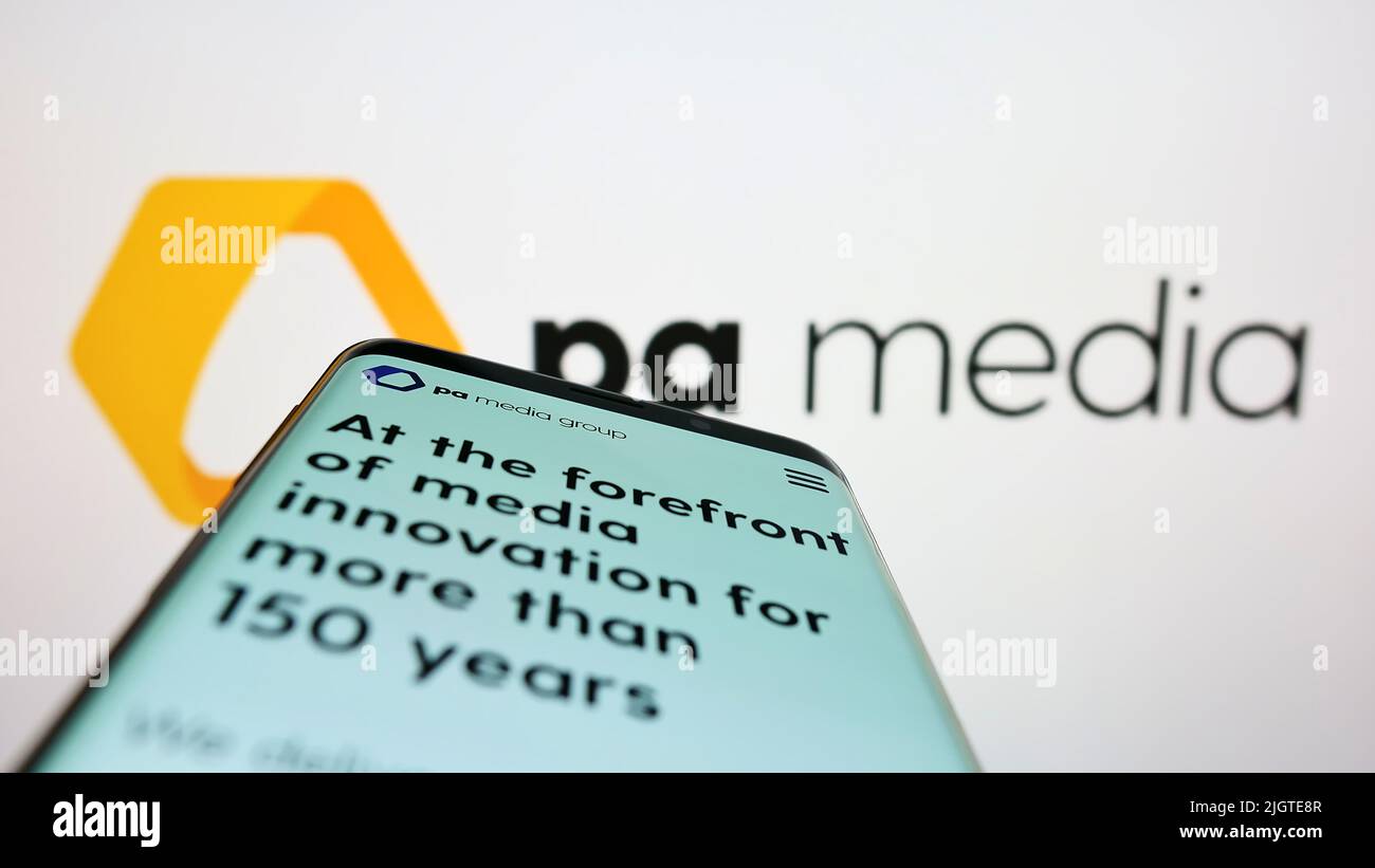 Smartphone with webpage of British news agency PA Media Group on screen in front of business