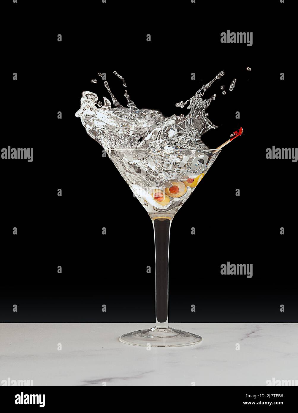 splashing dry martini with 2 green olives as garnish Stock Photo Alamy