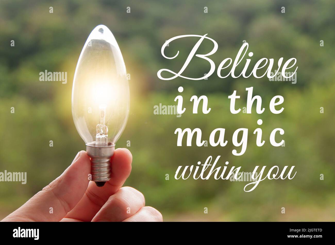 Motivational and Inspirational quote - Believe in the magic within you. Hand holding light bulb with blurred background. Motivational concept Stock Photo