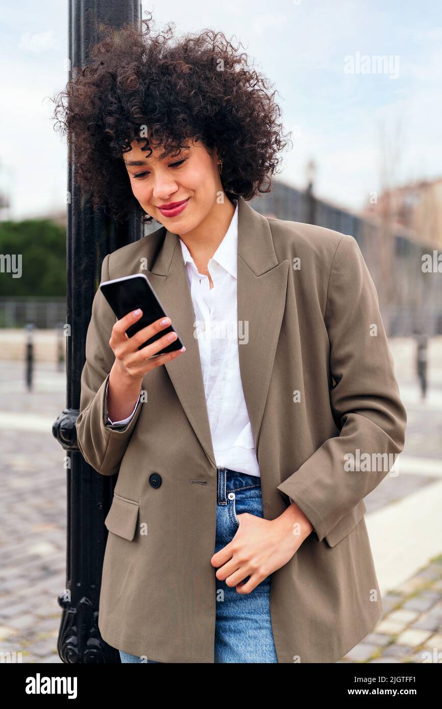 smiling young latin woman checking her phone Stock Photo