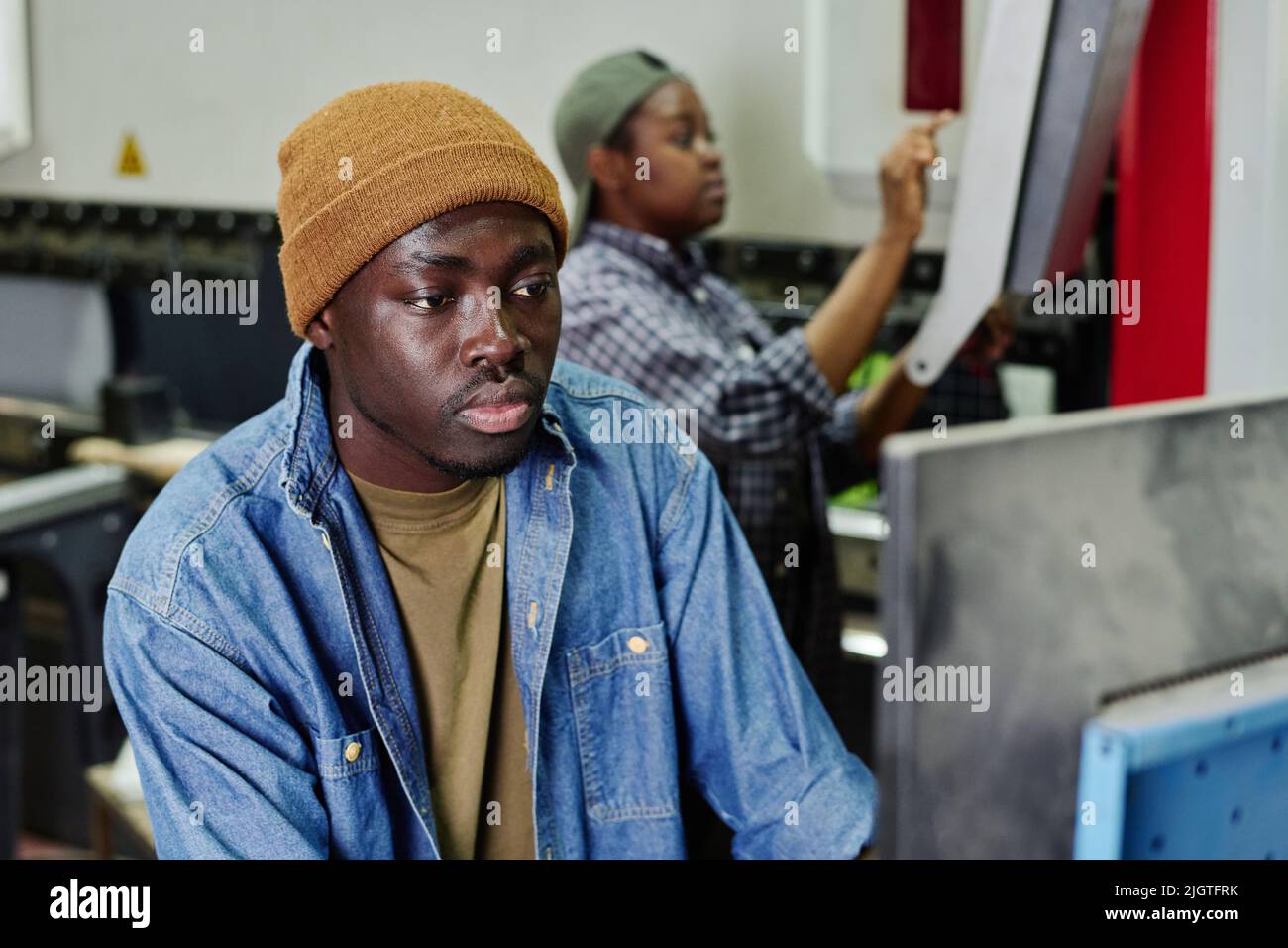 African operator choosing program on computer machine while working at plant Stock Photo