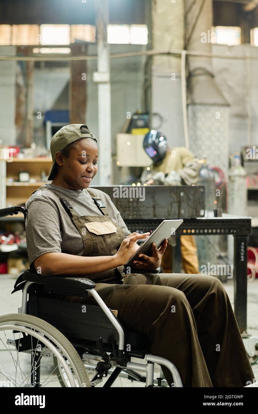 Female worker with disability using digital tablet to check items ...