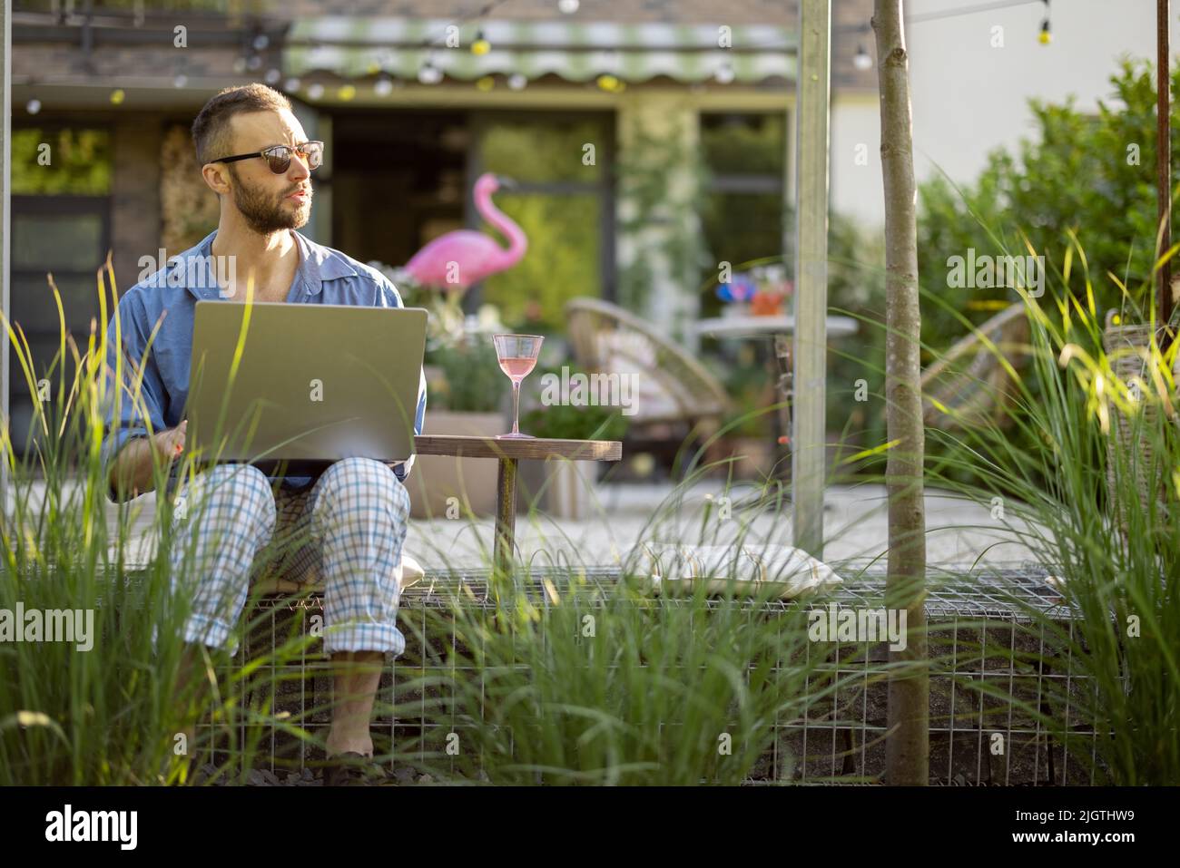 Man works on laptop while sitting at backyard Stock Photo