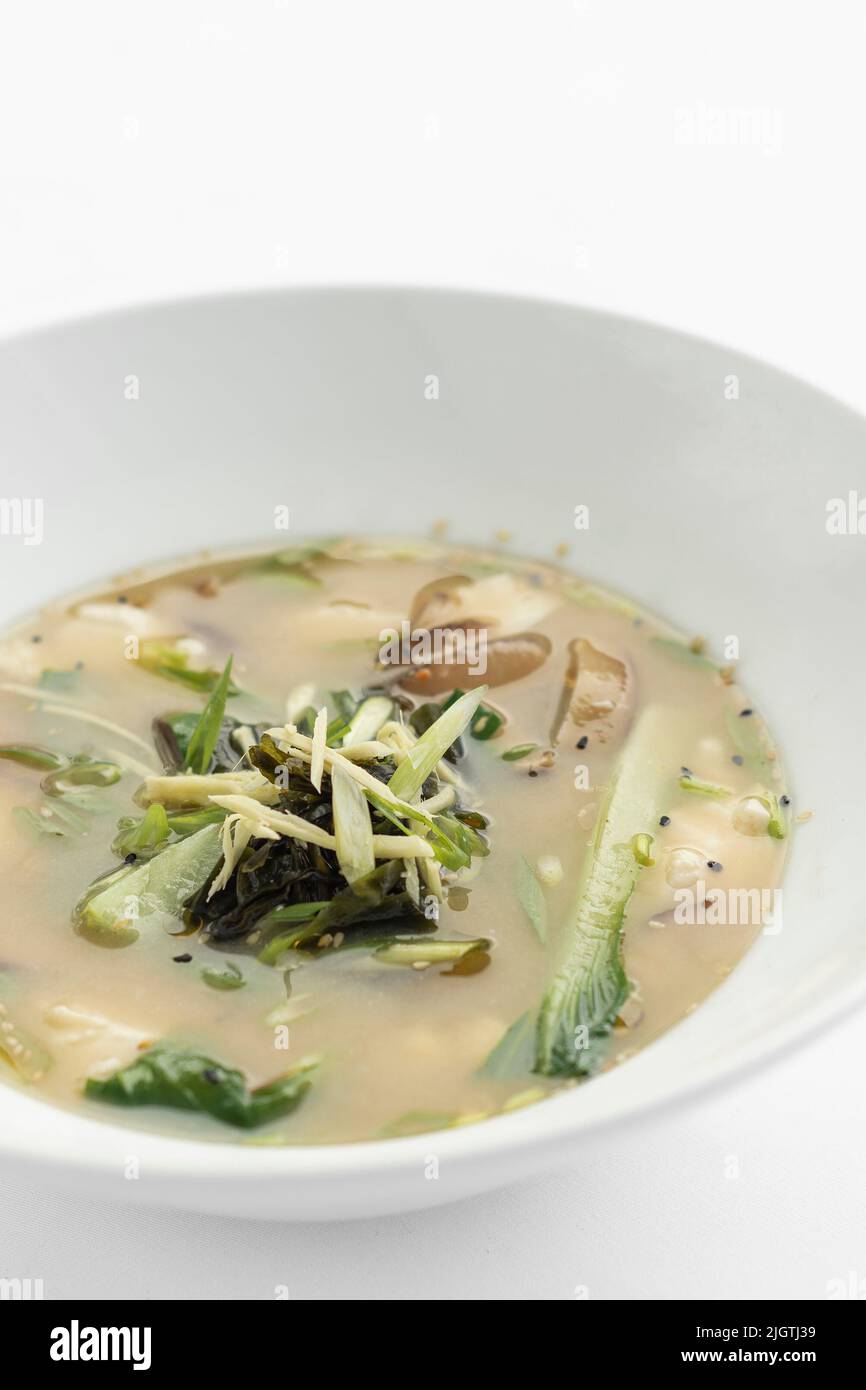 japanese miso soup with tofu, shiitake mushrooms, bok choy and seaweed on white background Stock Photo