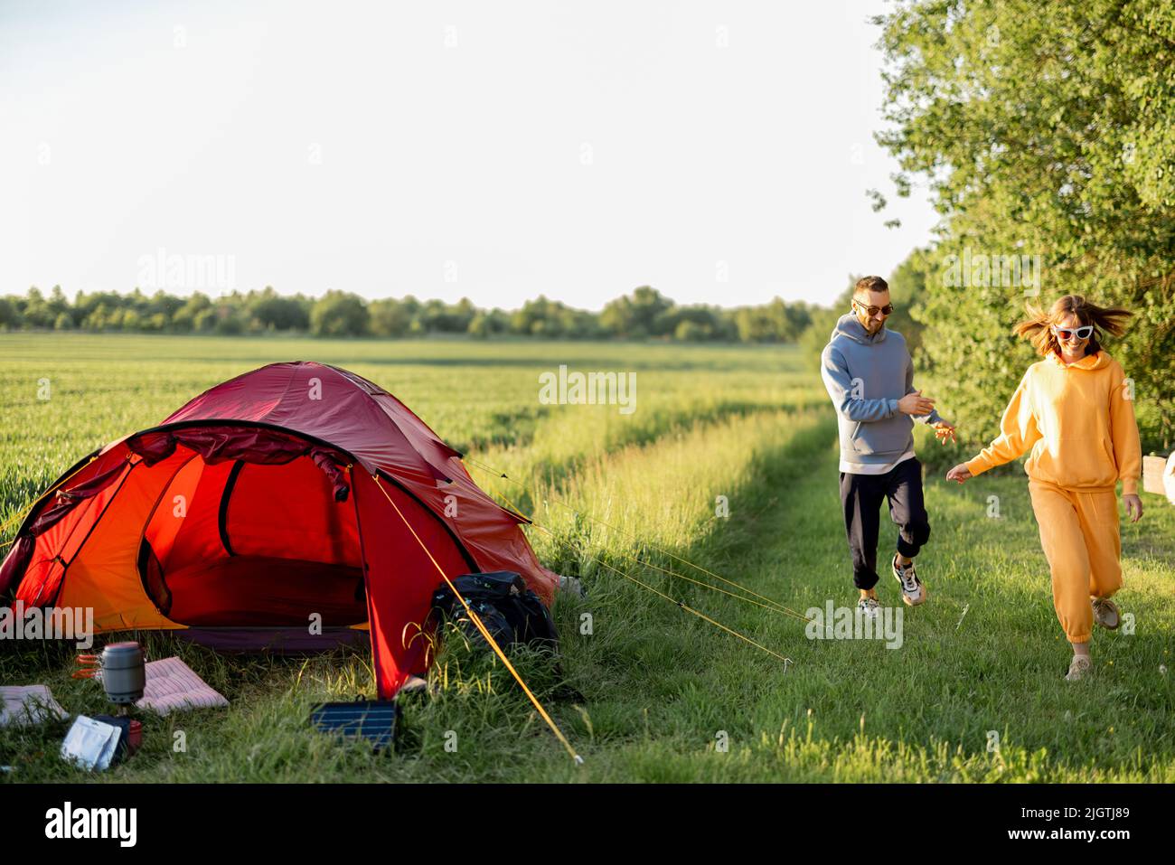 Young couple play with their dog at campsite Stock Photo