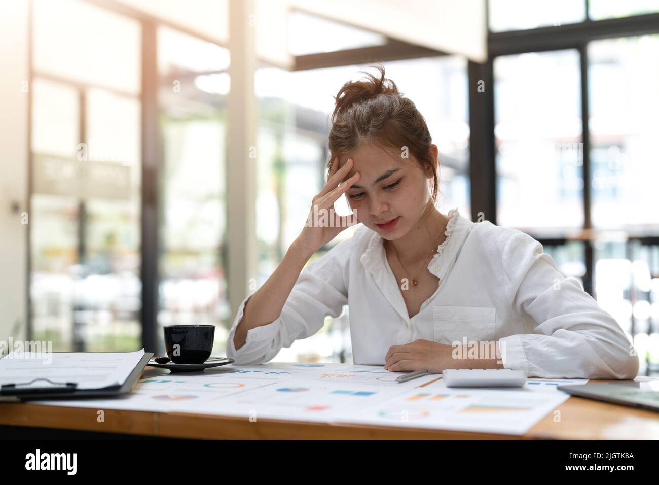 Young asian Woman Office Worker Uses Laptop, Feels Sudden Burst of Pain, Headache, Migraine. Overworked Accountant Feeling Project Pressure, Stress Stock Photo