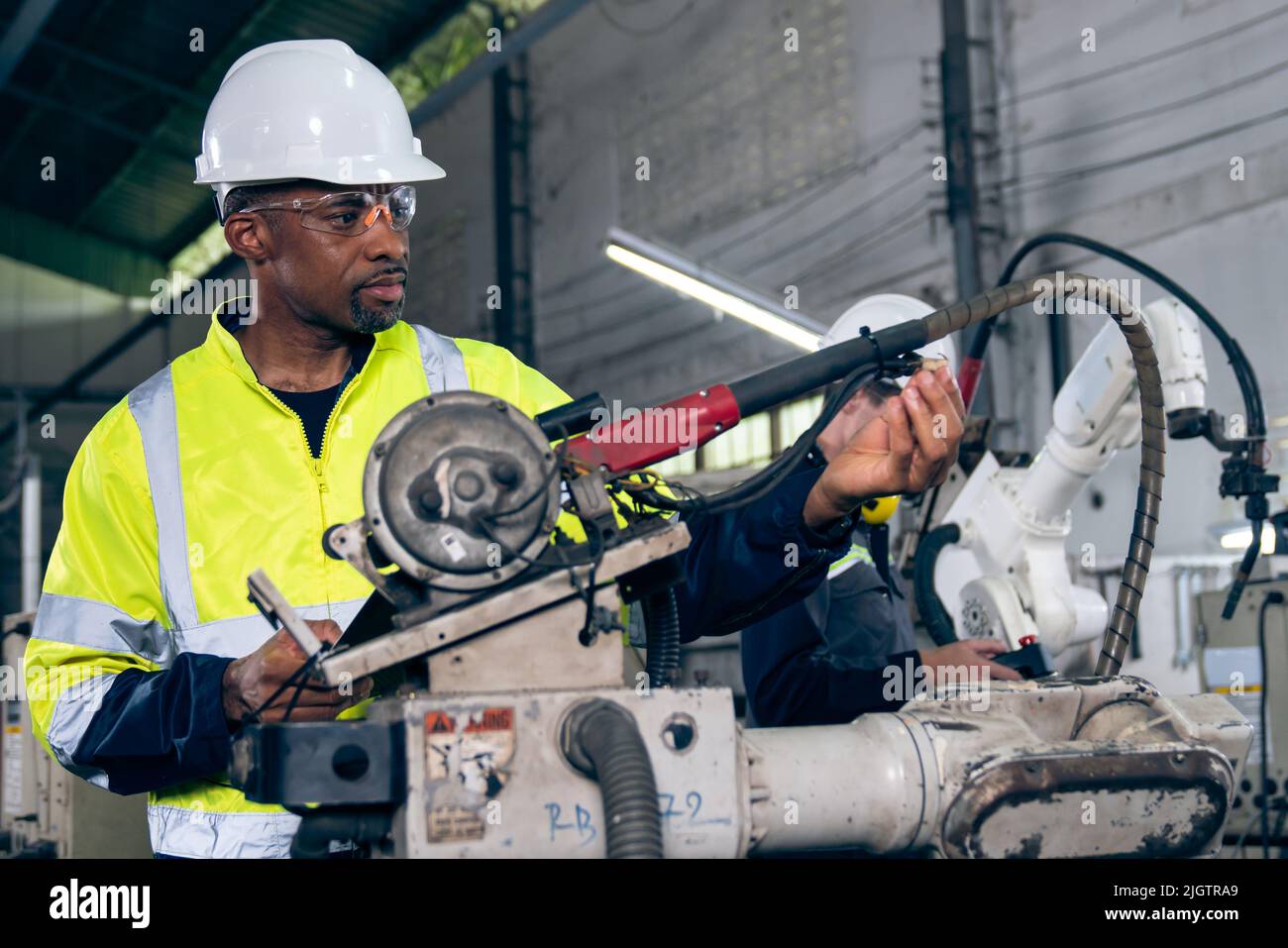 African American factory worker working with adept robotic arm in a