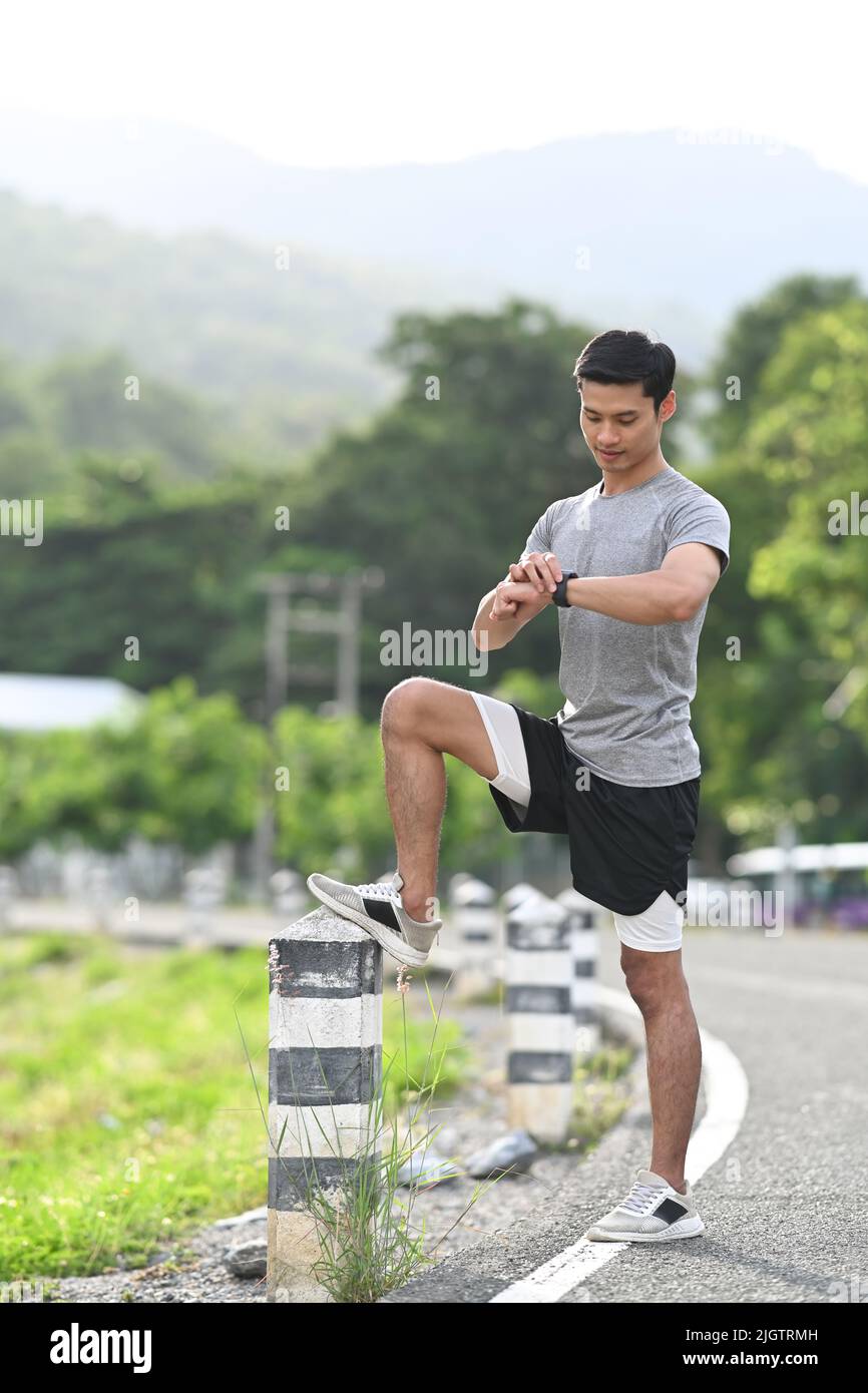 Athletic asian man resting and checking heart rate data on smartwatch