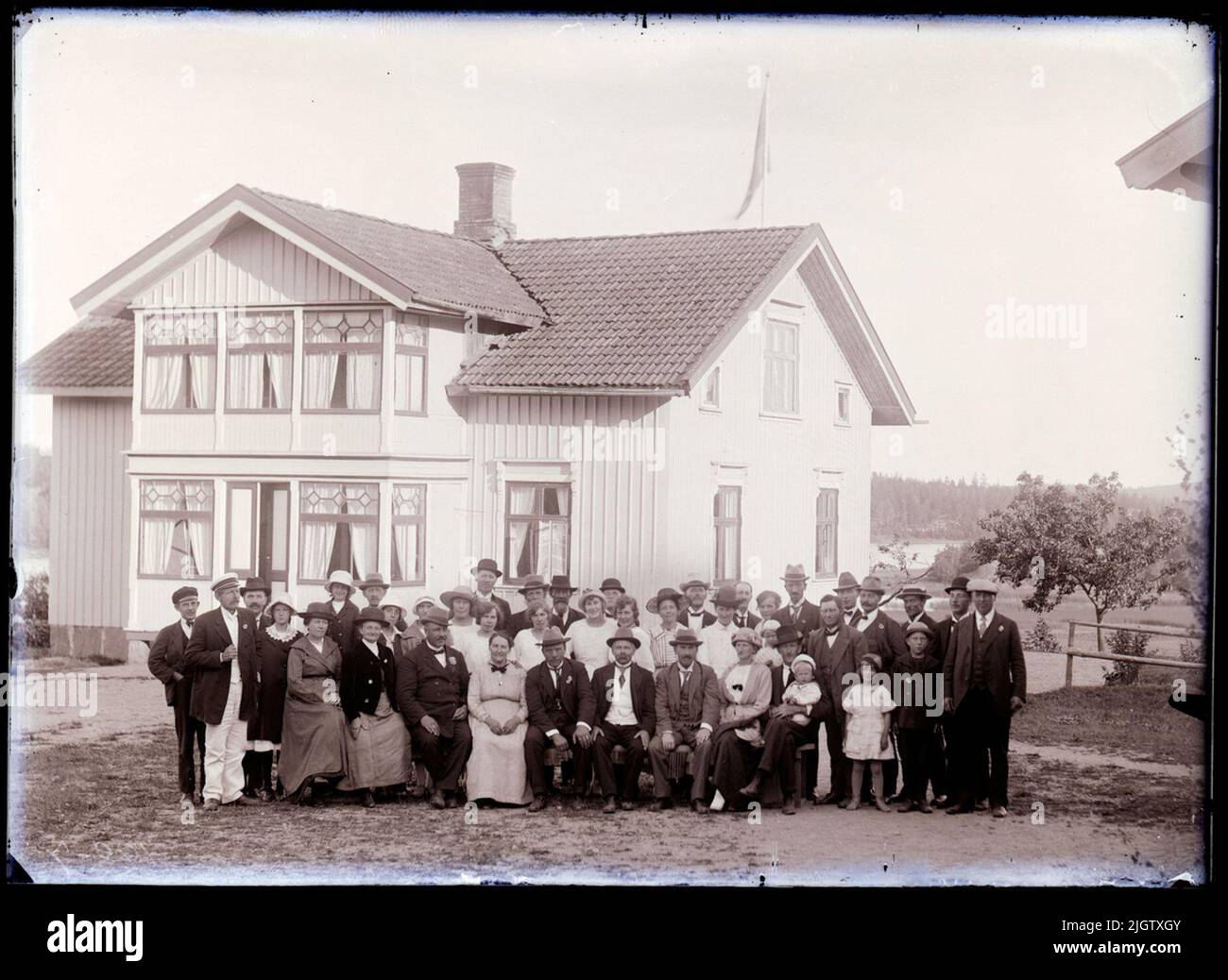 According to notes: 'July 19, 1921. Frisinnaded Association at Summer Meeting at Anders Pettersson at Elsedöd. . Row 2: Sören Grundberg (Young Man in Black Screen cap). No. 2 From left in white screen cap probably station champion A.H. Svahn. At the far right Axel Sohlberg (dressed in cap) Bakersta row: No. 8 Forest guard Albert Eriksson (hat and mustache ), Melker Hansson. ”The woman with striped dress and black hat can be Karin Elmér. A large group of people, 39 - 40, stand in front of a larger residential building. Sören Grundberg (1905-1998), Axel Sohlberg (1879-1941), Melker Hansson (1898 Stock Photo