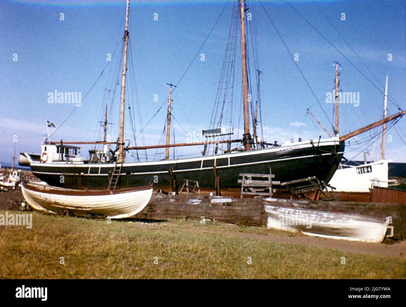 Written on the back: 'Polstjärnan by Motala, Farker Ring Andersen by Svendborg, Bygd by Ring Andersen 1904, Salgt Hit 1916, now redeemed to houseboat. 202/8' Photo of a ship in port. In the foreground, some dinghies are on land. Stock Photo