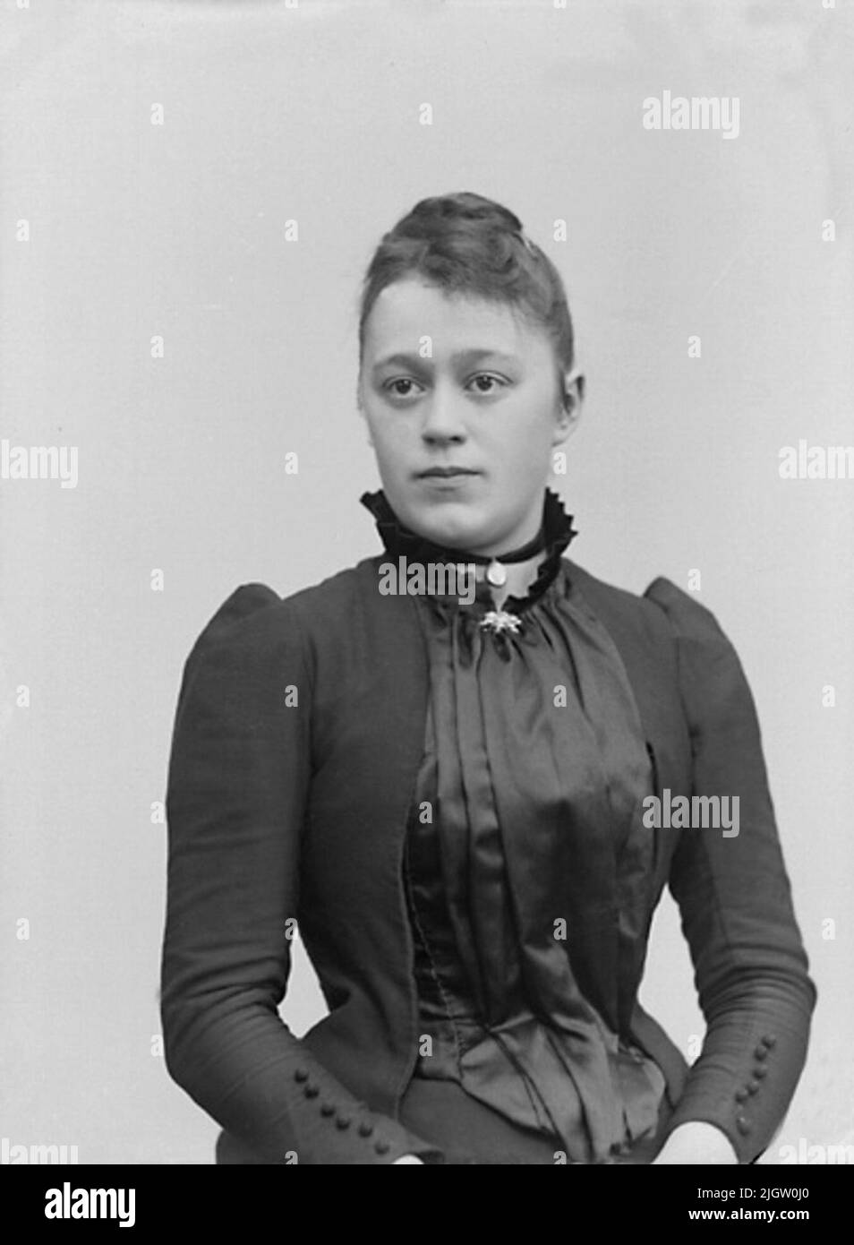 No. 215. Miss Elin Johansson, Trees, Ljungskile. 1894. Knee picture of a young lady in a black dress with a high collar. In the throat pit, a velvet band with medallion can be seen. Ateljéfoto. Stock Photo
