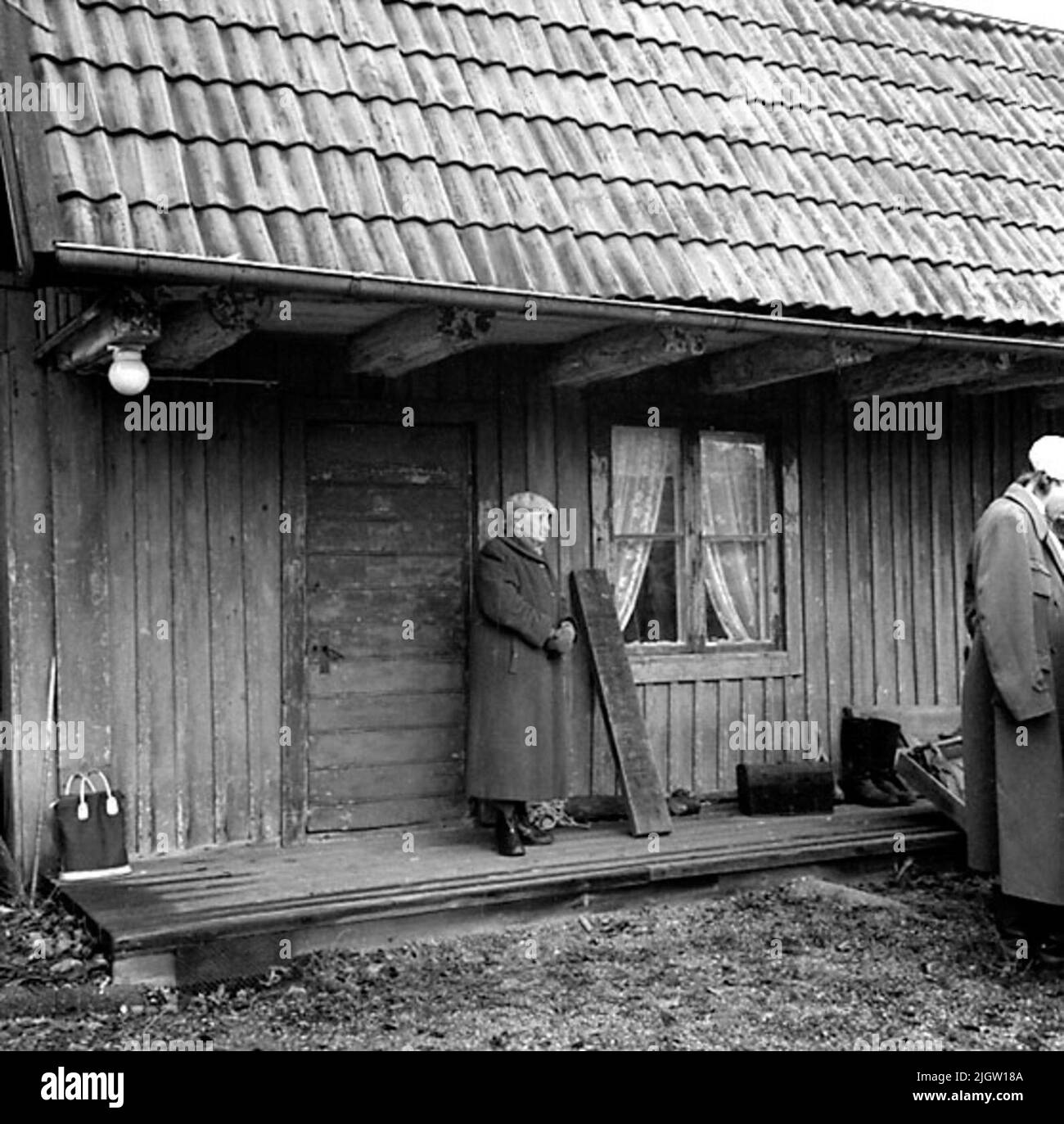 A woman stands on an overbuilding front in front of the door of an ...
