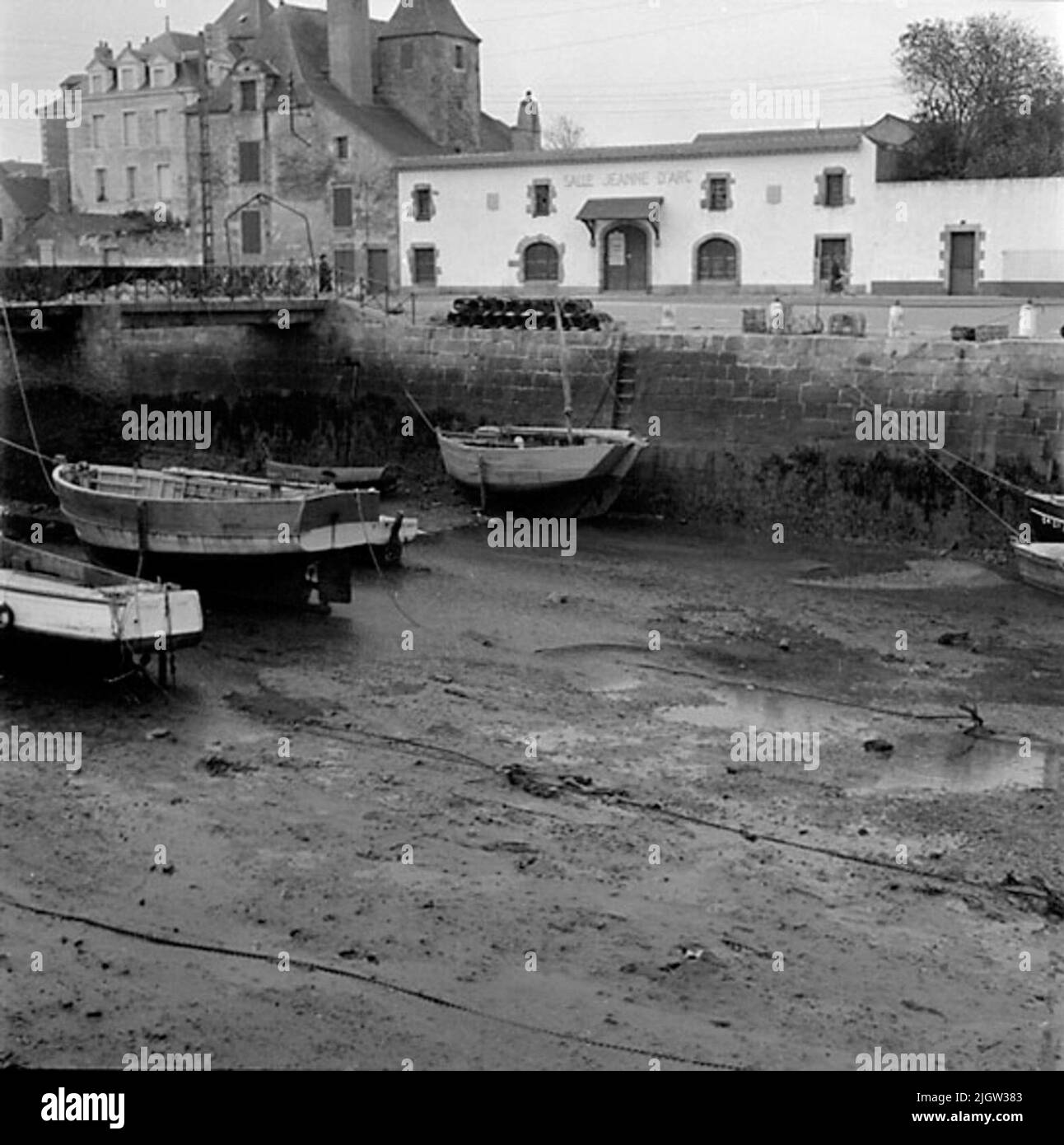 9. France. Photo journal is available at B.M.A. + Photo albums. Acquisition: Books and archive materials. Photos taken 1959-10-17.12 Pictures in series. According to notes: France. Atlantic coast, Le Croisic, 17/10 -59. Boats in the harbor channel at ebb. A number of boats are located in a port in a community. There is low tide so the boats are at the bottom of the harbor basin. Stock Photo